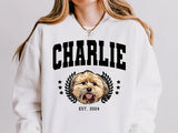 White sweatshirt with a dog graphic and 'CHARLIE EST. 2024' text on a plain background