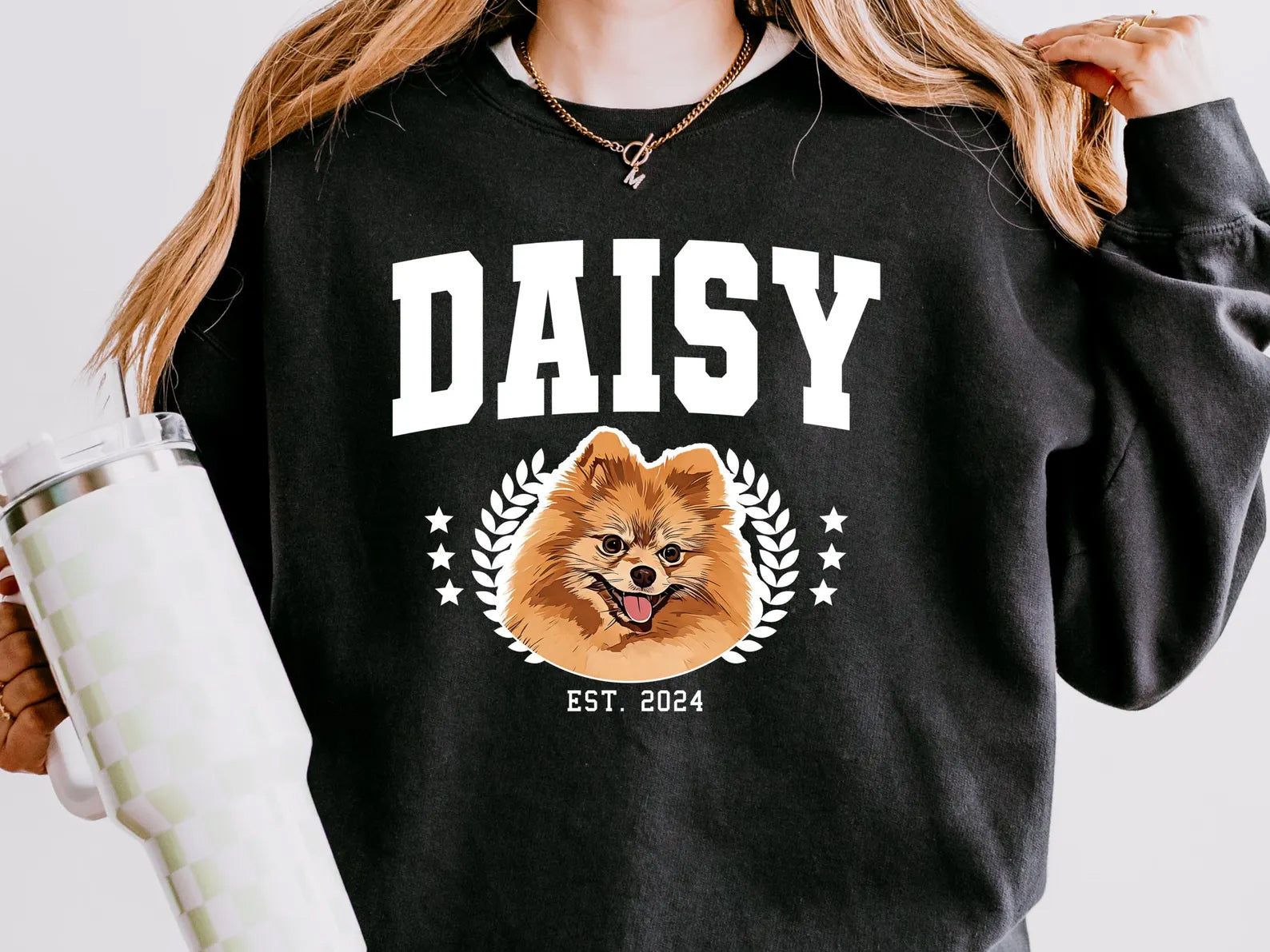 Person wearing a black sweatshirt with a dog graphic and 'DAISY EST. 2024' text.