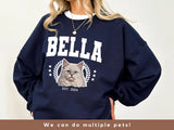Navy blue sweatshirt with a cat graphic and 'Bella' text on a plain background
